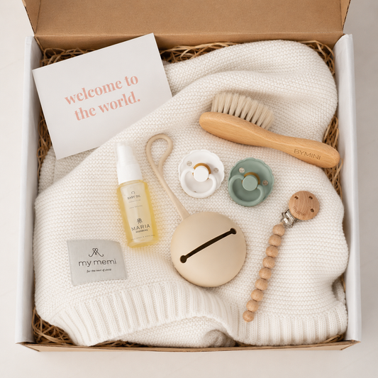 Vit babybox från BYMINI med stickad babyfilt, nappar, nappfodral, napphållare, babyolja och hårborste