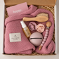 Rosa babybox från BYMINI med stickad babyfilt, nappar, nappfodral, napphållare, babyolja och hårborste