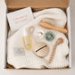 Vit babybox från BYMINI med stickad babyfilt, nappar, nappfodral, napphållare, babyolja och hårborste